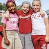 Three young girls wearing red, white and pink smiling for the camera at GAC summer camp