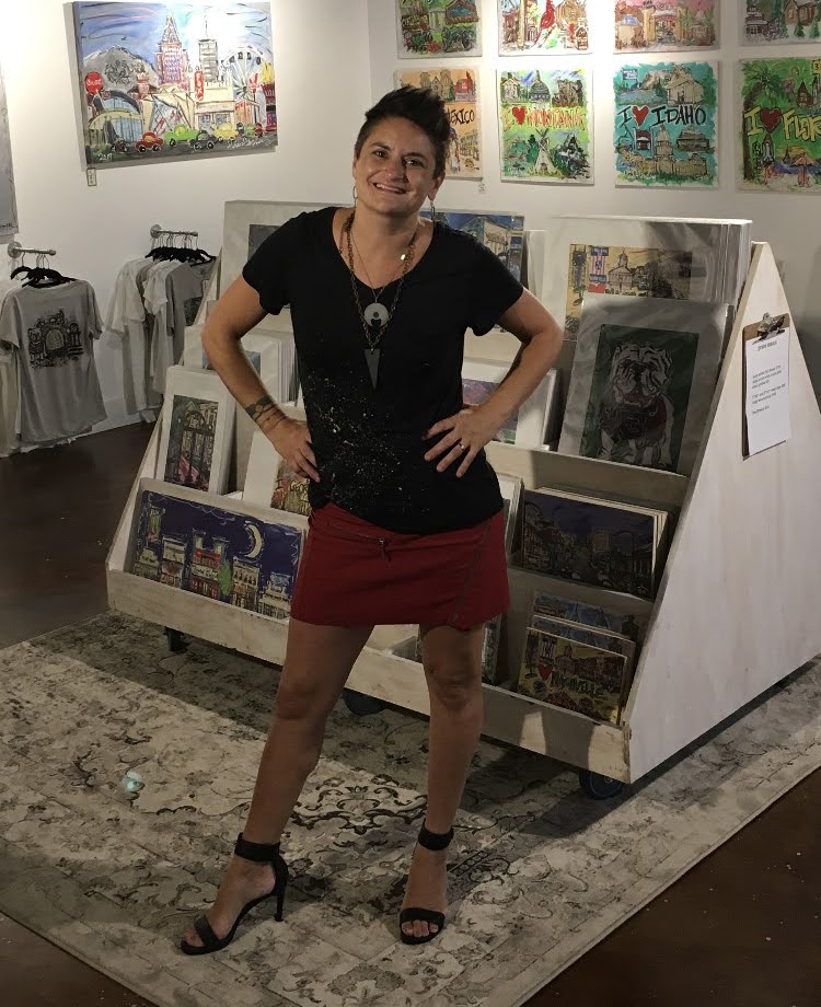 A woman with short dark hair wearing a dark top and red skirt standing in front of a display