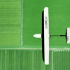 Overhead view of a white drone above a green farmland field.