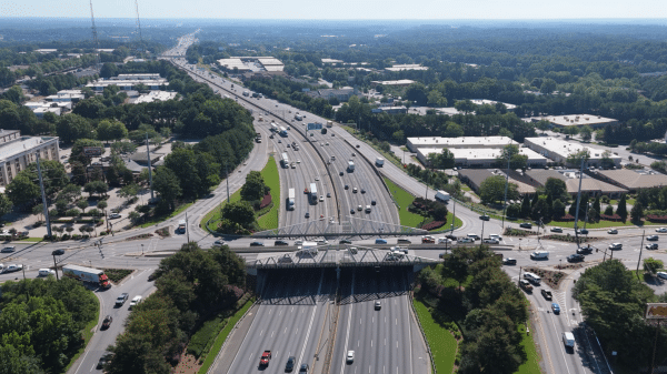 Aerial view of the 85 Gwinnett County corridor with highway, overpasses, cars, buildings and trees.