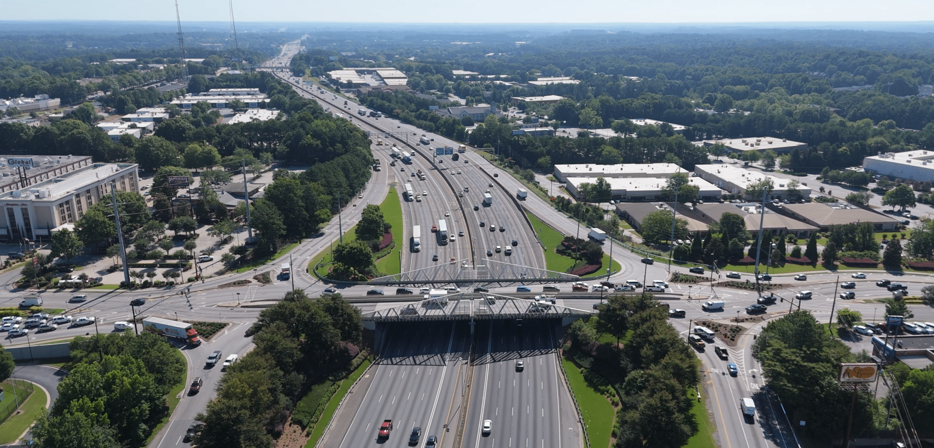 Aerial view of the 85 Gwinnett County corridor with highway, overpasses, cars, buildings and trees.