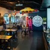 Interior of MET BrewMasters coffee shop with dark floor, a row of tables and Beatles memorabilia.