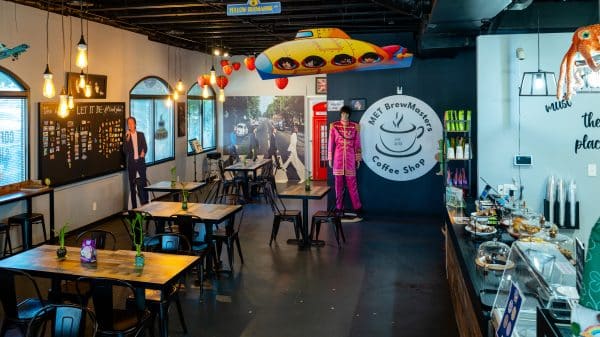 Interior of MET BrewMasters coffee shop with dark floor, a row of tables and Beatles memorabilia.