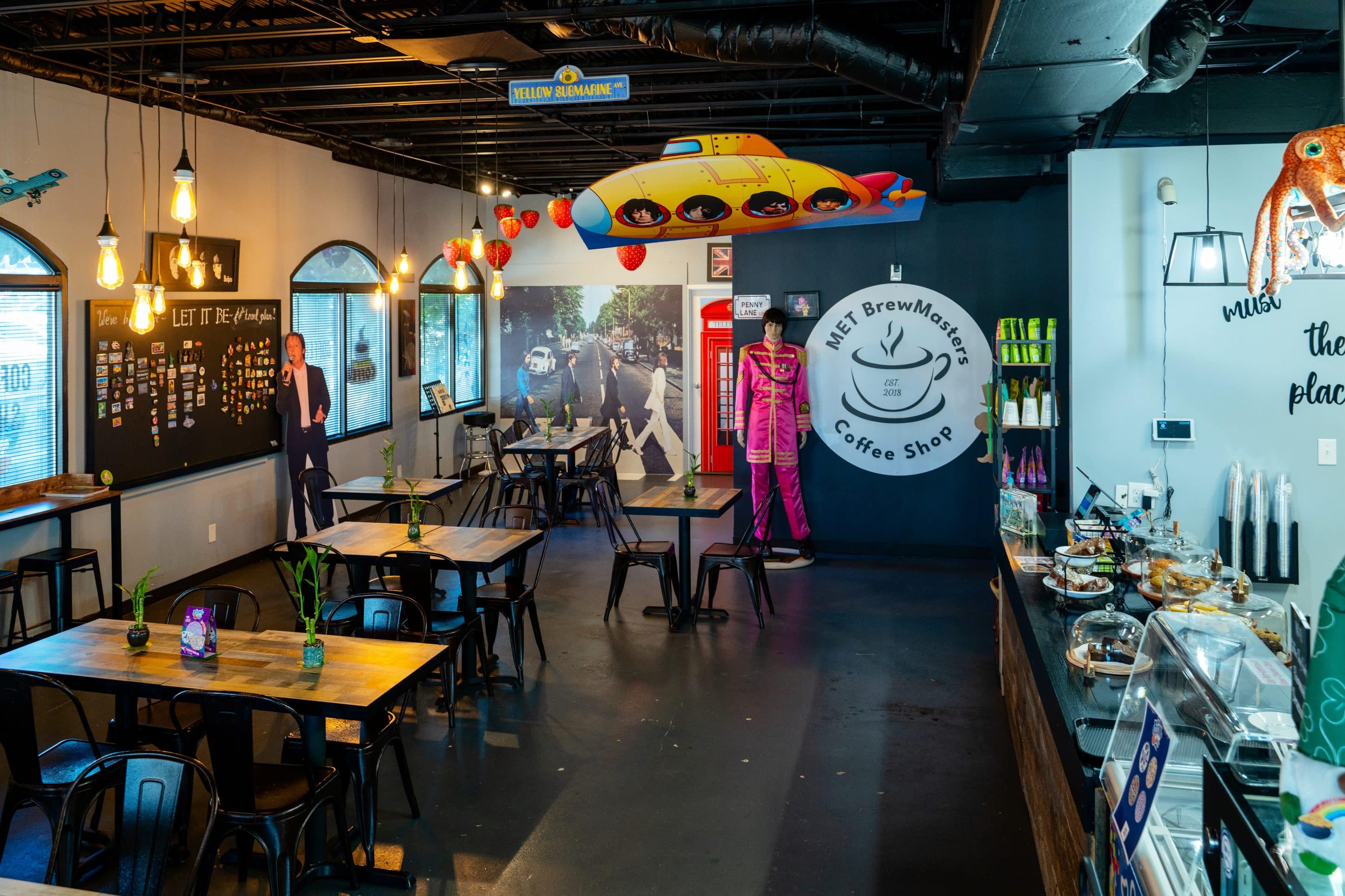 Interior of MET BrewMasters coffee shop with dark floor, a row of tables and Beatles memorabilia.