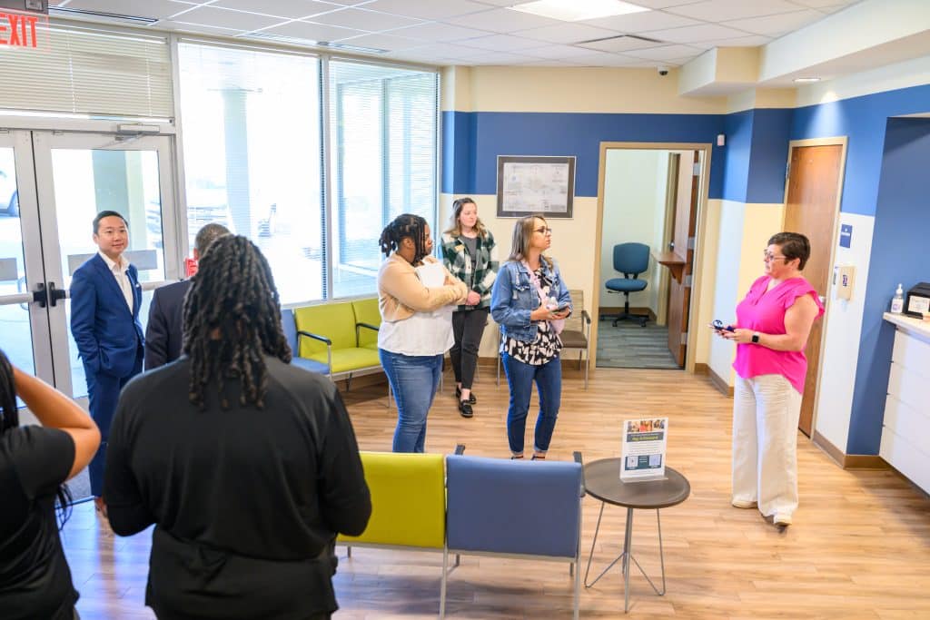 A group of people in the lobby of a new healthcare center preparing to take a tour of the space after a ribbon cutting ceremony.
