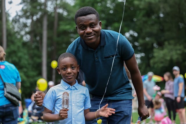 A Black dad and his son having fun at the Dunwoody Kids to Parks Day festivities in Dunwoody, Georgia in 2024.