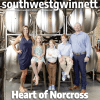 Cover of the June/July issue of Southwest Gwinnett magazine with the magazine name at the top, Heart of Norcross in white type at the bottom and a photo of a man and woman with their three kids in front of brew tanks at Cultivation Brewery.