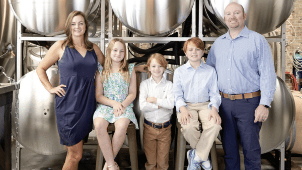 Cover of the June/July issue of Southwest Gwinnett magazine with the magazine name at the top, Heart of Norcross in white type at the bottom and a photo of a man and woman with their three kids in front of brew tanks at Cultivation Brewery.
