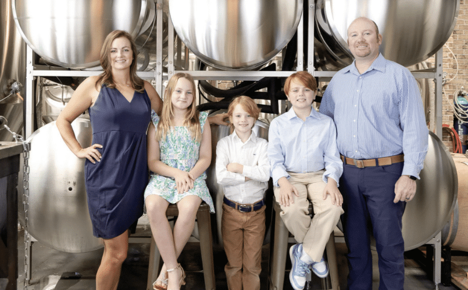 Cover of the June/July issue of Southwest Gwinnett magazine with the magazine name at the top, Heart of Norcross in white type at the bottom and a photo of a man and woman with their three kids in front of brew tanks at Cultivation Brewery.