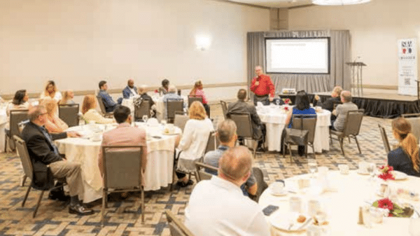 An audience of people sitting at tables in a hotel meeting space listening to Tim Echols speak about energy in Georgia.